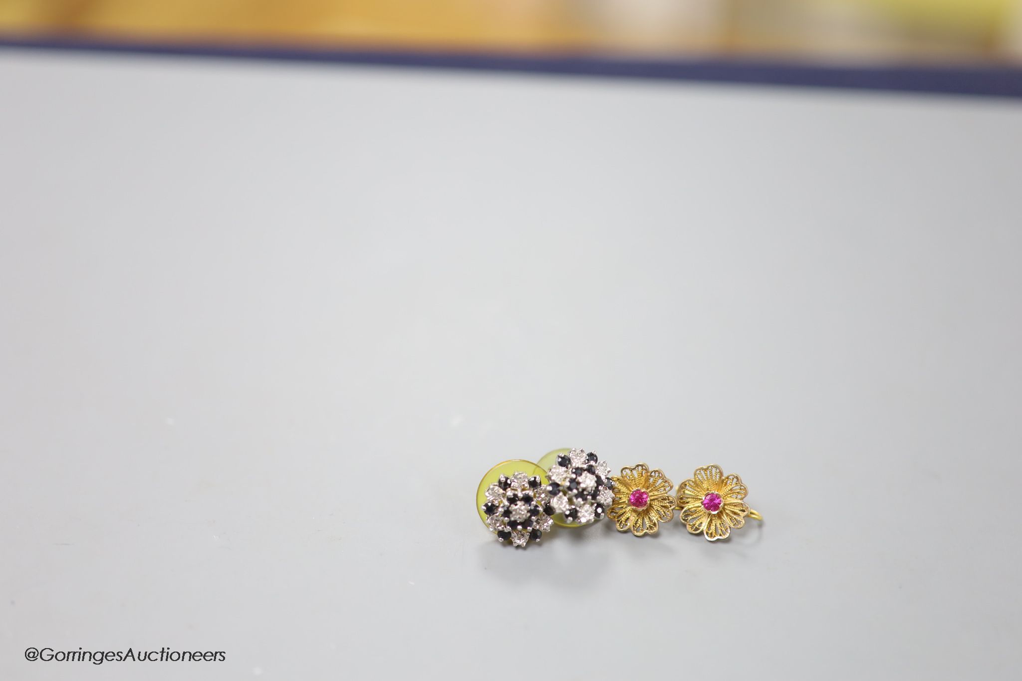 A pair of 9ct sapphire and diamond cluster set ear studs, gross 3.1 grams and a pair of yellow metal and gem set filigree earrings, gross 2.8 grams.